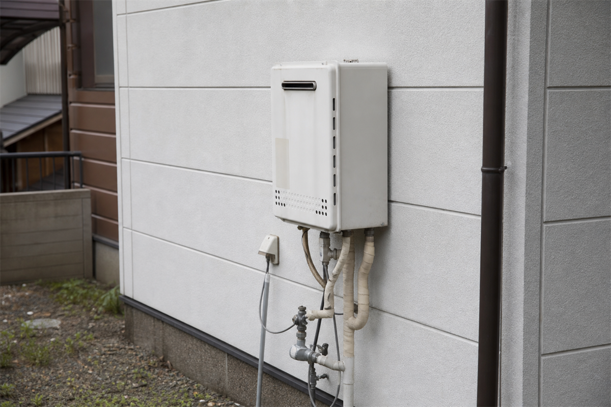 屋外給湯器の設置状態を離れて確認する様子